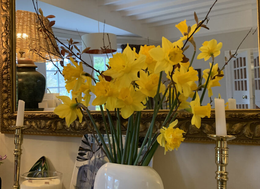 White vase of daffodils on a mantle piece